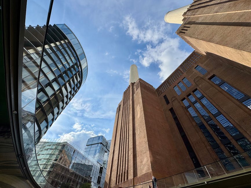 An upward view of a modern urban courtyard featuring a mix of architectural styles, including a contemporary glass building with curved balconies on the left and a historic brick structure with vertic