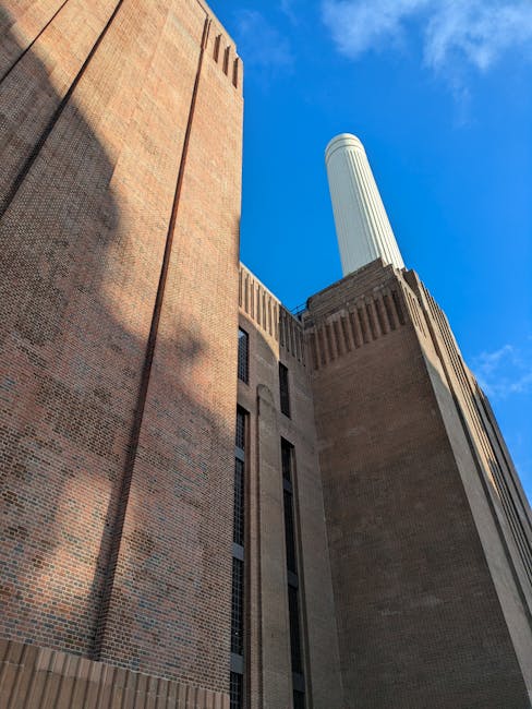 An upward view of a modern urban courtyard featuring a mix of architectural styles, including a contemporary glass building with curved balconies on the left and a historic brick structure with vertic
